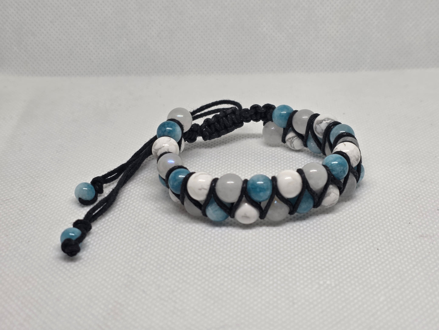 Larimar (colored), Howlite, and moonstone adjustable bracelet on a white background